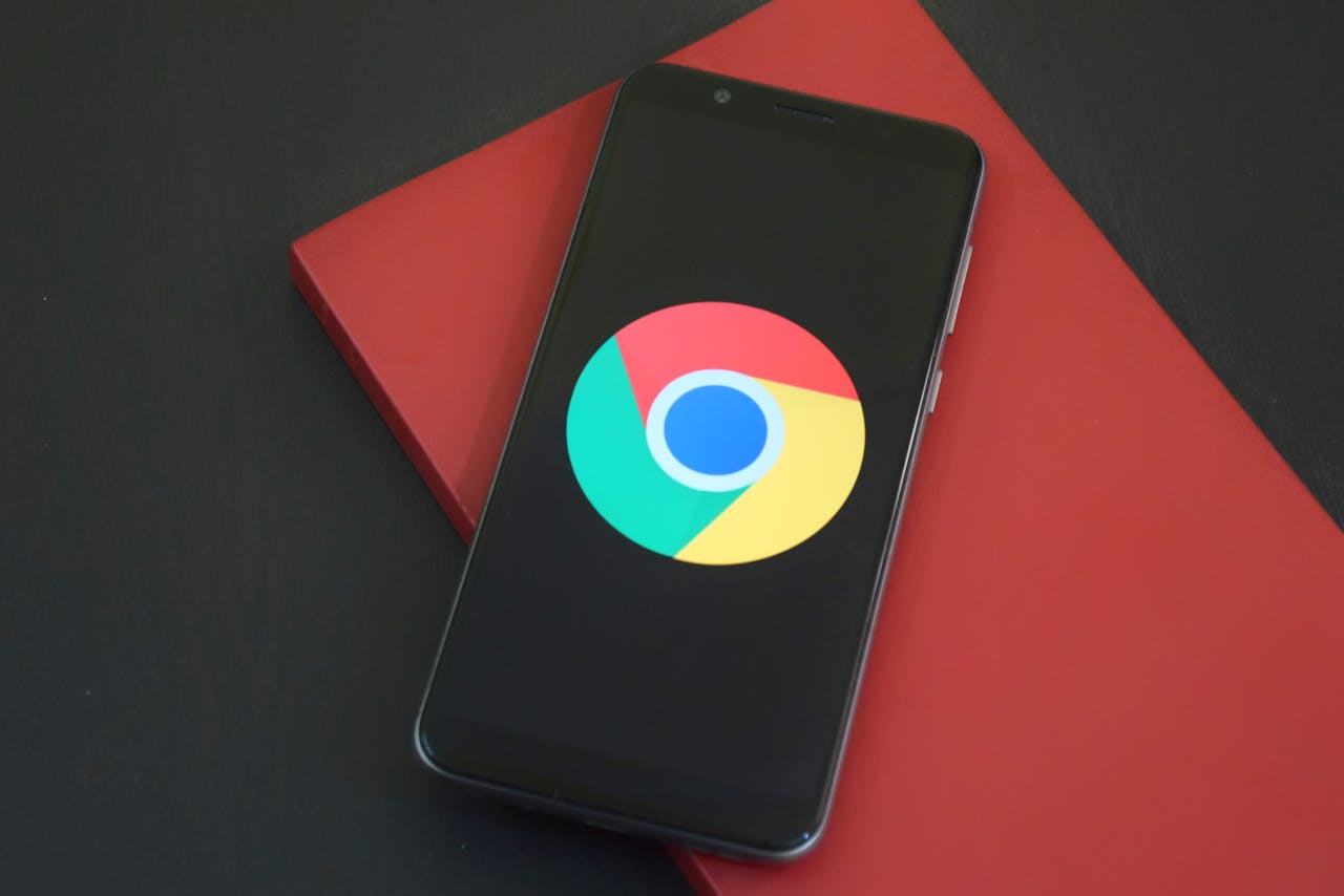 contact-img-01 Close-up of a smartphone with Chrome browser logo on screen placed on a red notebook.